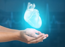 Female hands with heart on blue background. Cardiology concept.