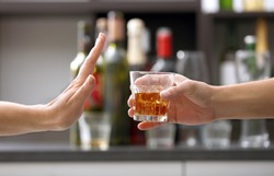 Female hand rejecting glass with alcoholic beverage on blurred background