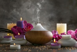 Aroma oil diffuser, candles and flowers on table