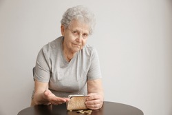 Senior woman counting coins while sitting at table. Poverty concept