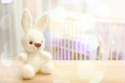 Knitted toy bunny and blurred baby room on background. Holidays celebration concept