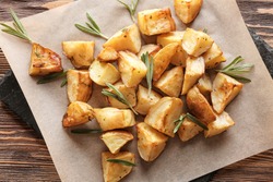 Delicious baked potatoes with rosemary on slate plate, closeup
