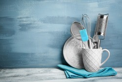 Kitchen utensils in cup on table against wall