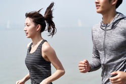 young asian couple man and woman jogging outdoors by the sea