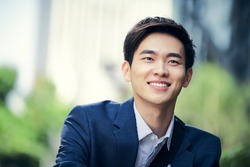 outdoor portrait of a successful asian business man happy and smiling