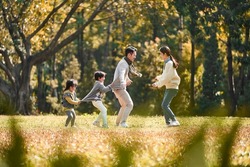young asian family with two children having fun playing game outdoors in park