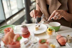 close-up shot of hands of a female asian customer eating desserts at a fining dining restaurant