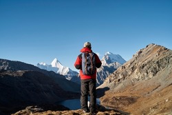 rear view of asian man backpacker male hiker looking at mountains in yading national park, daocheng county, sichuan province, china