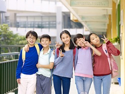 group of happy smiling primary school student posing on corridor of classroom building.