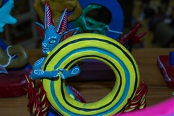 The alebrije is holding on to the letter o and looking to the side.