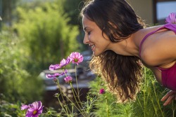 Young beautiful woman smells a flower in the garden