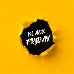 Black Friday text in paper hole teared in yellow paper over black background