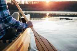 Close up of hipster girl holding canoe paddle. Canoeing on the sunset lake
