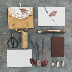 Flat lay of different object on vintage background. Craft brown bag, empty blank and tools. DIY concept. Homemade invitation card. Rustic style for wedding 
