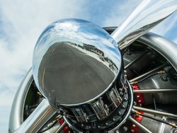 Historic fighter plane engine with close up of reflection of runway and airfield in the nose of the propeller