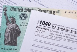 US Treasury stimulus check laying on a form 1040 tax return for 2020 to illustrate questions about qualification for payment