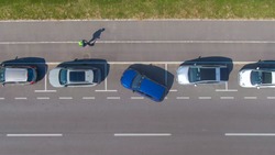 AERIAL, TOP DOWN: Unrecognizable person tries to parallel park their car into a tight roadside parking spot. Driver attempts to back their vehicle into a parking space at the side of the street.