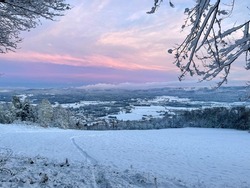 Picturesque shot of the gorgeous wintry countryside on a colorful December morning. Breathtaking pink hued winter morning sky spans above idyllic white rural landscape. Christmas fairytale in Slovenia