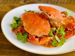Steamed crabs on a bed of spicy tomato sauce, garnished with parsley