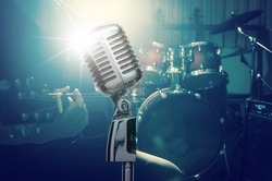 Retro microphone over the musician playing the guitar on band background with spot light, musical concept