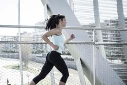 young beautiful and athletic sport woman running and jogging in urban training workout crossing modern metal city bridge in female runner body care and healthy lifestyle concept 