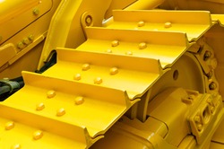 Bulldozer tracks and drive gear with sprocket mechanism, large construction machine with bolts and yellow paint coating, heavy industry, detail