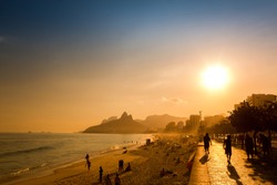 Unidentifiable silhouettes enjoy late afternoon sun rays on Ipanema beach in Rio de Janeiro, Brazil. Ipanema is one of the most expensive places to live in Rio