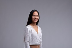 Attractive toung woman with a friendly smile and long dark hair wearing a stylsih white lacy top in an upper body portrait