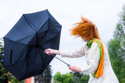 A woman tries to hold her umbrella in a strong wind