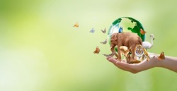Earth Day or World Wildlife Day concept. Save our planet, protect green nature and endangered species, biological diversity theme. Group of wild animals and flock of butterflies with globe in hand.