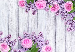 Lilac flowers with wild roses on background of shabby wooden planks 