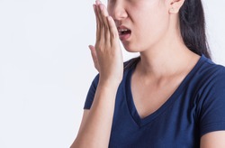 Asian woman checking her breath with her hand on white background.