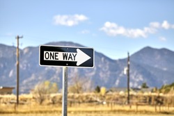 One way road sign with blurred mountains background.