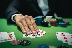 Man dealer or croupier shuffles poker cards in a casino game card, and chips on green table. poker game concept
