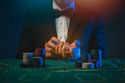 Man dealer or croupier shuffles poker cards in a casino on the background of a table,asain man holding two playing cards. Casino, poker, poker game concept