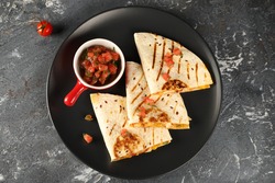 Quesadilla with chicken, cheese and vegetables, served with sauce of fresh tomatoes, top view.