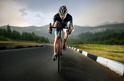 A young man trains on a road bike, in the mountains.