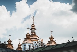 Photo of a Great Beautiful St. Michael's Cathedral with its Famous Golden Domes over White Fluffy Clouds. Ukrainian Orthodox Church in Kyiv.