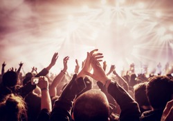 Vintage style photo of a crowd, happy people enjoying rock concert, raised up hands and clapping of pleasure, active night life concept