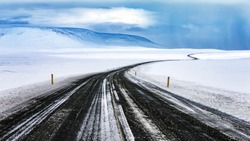 Snowy road, long curved highway among beautiful white snowy landscape, winter travel, beautiful nature of Iceland