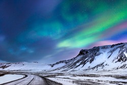 Beautiful landscape of the northern lights over hight mountains covered with snow,  Aurora Borealis, wonderful phenomena of nature, winter time in Budir, Iceland