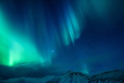Amazing view on the Northen light over high mountains covering with snow, forces of nature, Aurora Borealis, Iceland