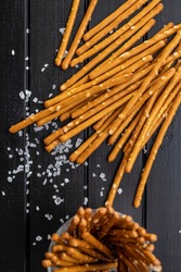 Salty sticks. Crunchy pretzels on black wooden table. Top view.