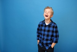 Happy kid , laughing boy. Happy, smiling boy on a blue background expresses emotions through gestures.