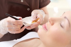 Chemical peeling, exfoliating treatment. Beautician imposes on the woman's face a cosmetic preparation. 