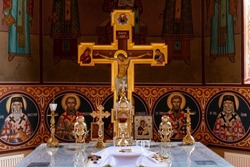 Inside the altar of an orthodox church, with traditional artifacts and the richly decorated cross and walls.