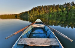 fishing boat in a calm lake water/old wooden fishing boat/ wooden fishing boat in a still lake water