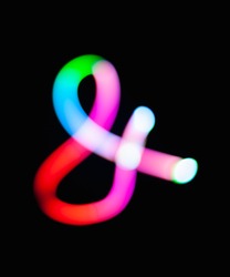 Glowing ampersand symbol & logogram on dark background. Abstract night light painting. Creative artistic colorful bokeh. New Year. Use  to build you own design for book cover, CD poster or post card