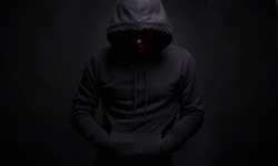 Man in Black Hood in dark studio. Boy in a hooded sweatshirt. Male portrait