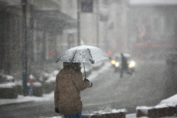 Man with umbrella during snow storm in the street